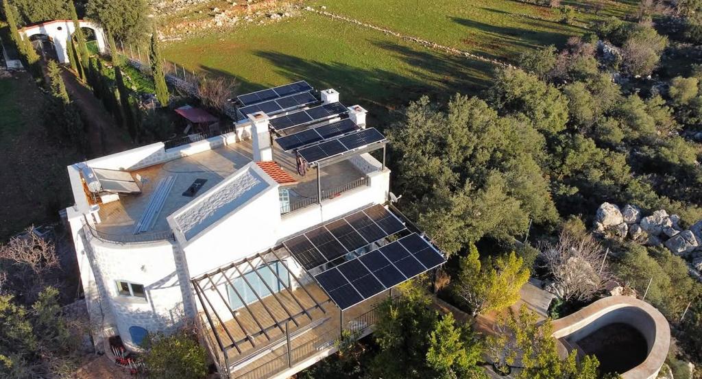 A villa in Balikesir with a rooftop 18 kWp solar panel system integrated harmoniously into its natural surroundings.